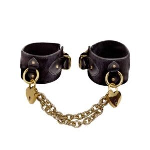 Leather handcuffs in black with soft hair, golden heart-shaped padlock and golden chains to connect the two bracelets.