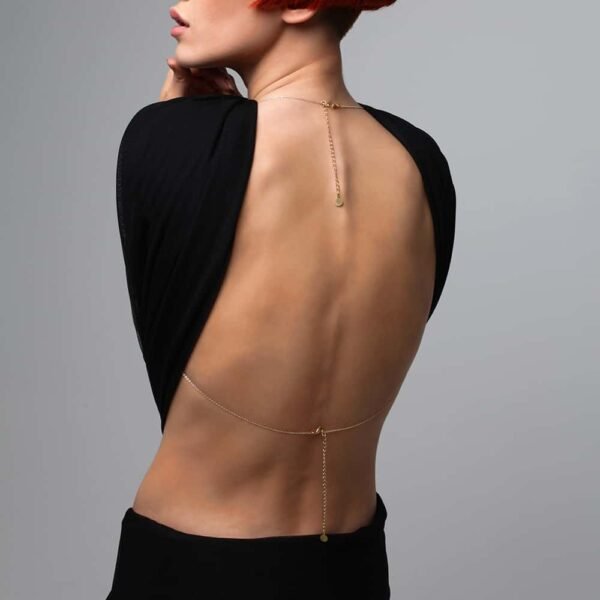 Gold body jewelry crossed between breasts and bare back at Brigade Mondaine