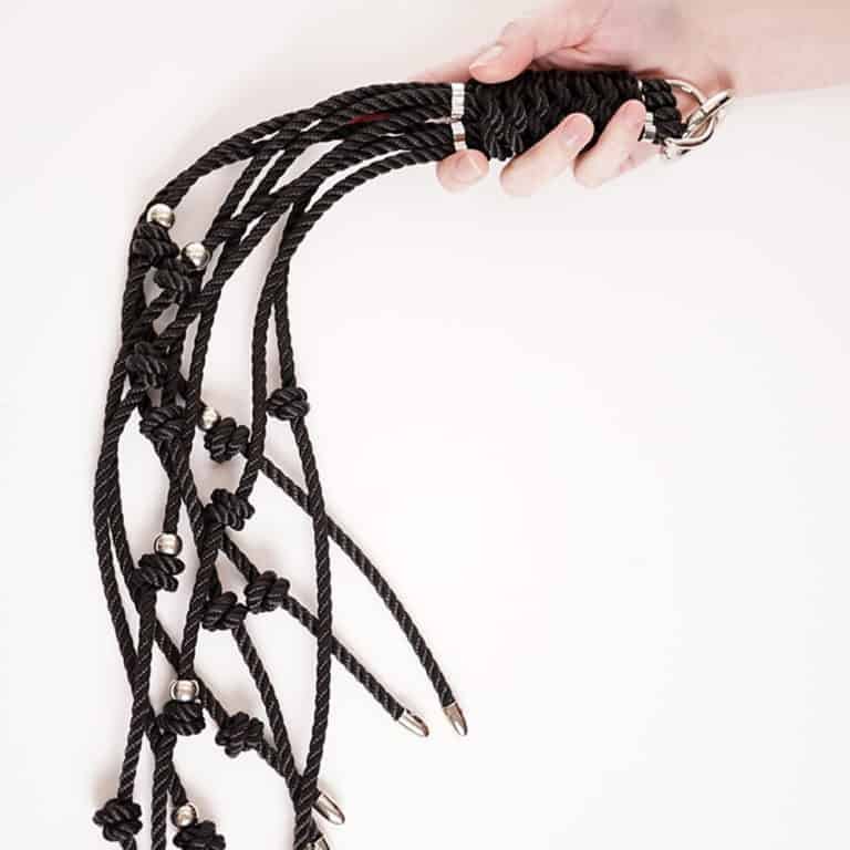 Fouet en cordes noires avec petits noeuds et détails en argent pour plus de sensations