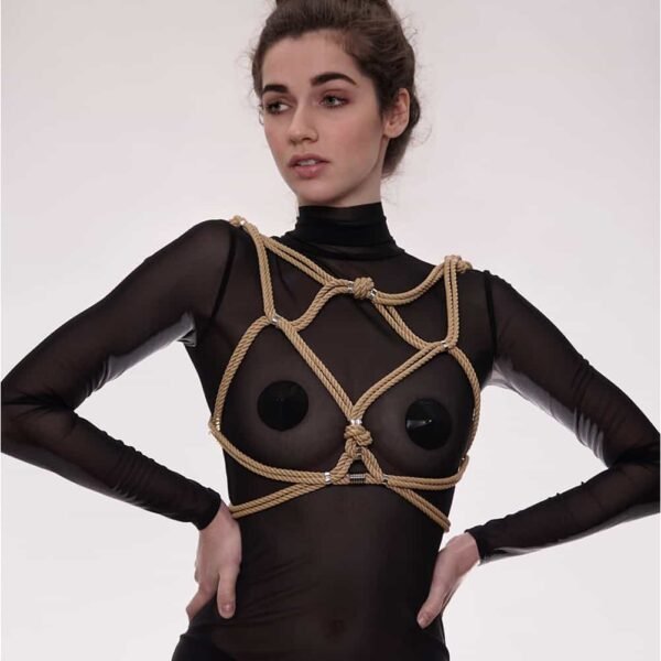 Hoshi harness from Figure of A in beige color. This piece is made from waxed cotton ropes and silver beads in zinc and brass alloy. It is worn over the ribcage and contains an interlacing of ropes that wrap around the breasts and waist.