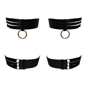 You can see here the DALA GARTERS RING from the brand Bordelle. The front is composed of a thick black satin band. This band is divided into 2 parts. On one part it is whole and on the other it is divided into 3 small strips. These parts are delimited by a perpendicular band with a gold plated ring at the end. The backside is very similar. It is divided into 2 parts as well. One with the whole band and the other with 3 small bands. Each band has a gold plated detail to adjust it.