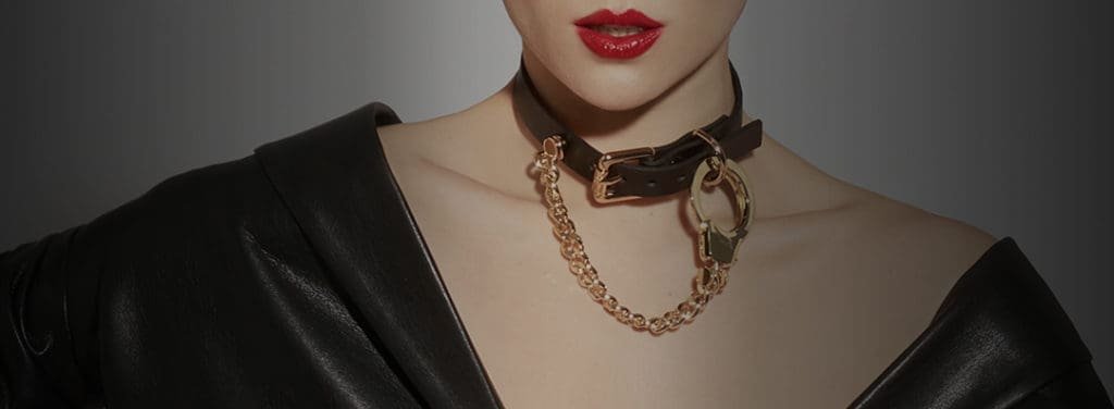 Necklace Handcuffs chains and leather of the brand ELF ZHOU LONDON. The necklace is attached around the neck of the mannequin. The leather part of the necklace is attached and the gold chain attached to the necklace by the gold cuff hangs.