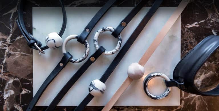 Leather necklace in black and beige, thin band and a thick collar. On each necklace is a ring or a ball with a marble pattern.